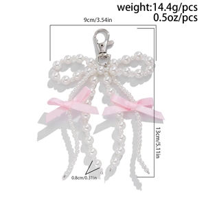Detailed view of pink ribbon bow keychain with pearls and size measurement specs