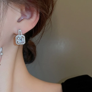 Detail view of shimmering square geometric zircon stud earrings worn on a model's ear