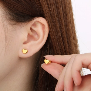 Boucles d'oreilles cœur dorées en acier inoxydable montrées sur l'oreille et en main