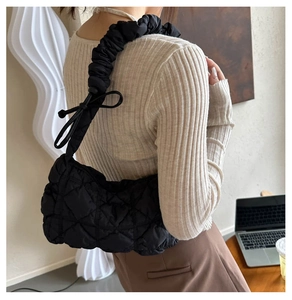 Gros plan sur le sac matelassé noir brillant avec sa poignée froncée style nuage