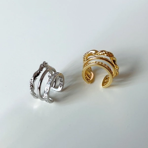 Detailed view of triple-layered silver and gold ear cuffs with zircon inlays and textures