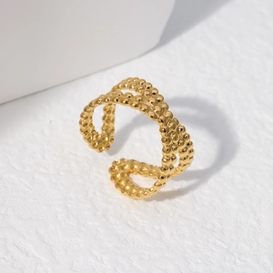 Dettaglio dell'anello dorato a doppio strato con texture a sfere e design aperto
