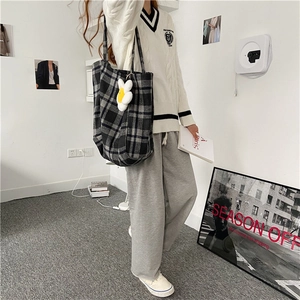 Detail of grey plaid woolen tote bag with white daisy charm in casual outfit style
