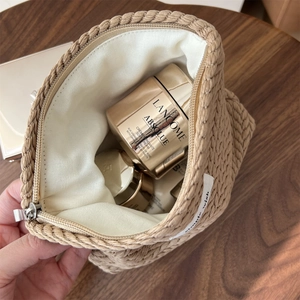 Macro shot of spacious inner capacity and metal zipper on beige woven makeup pouch