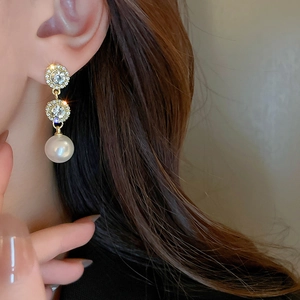 Detail of luxury gold drop earrings with micro-pave crystals and round white pearls