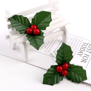 Artificial Christmas holly leaves and red berries set on a decorative white bench