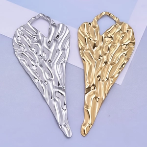 Détail de pendentifs en forme de cœur dorés et argentés avec une texture plissée unique