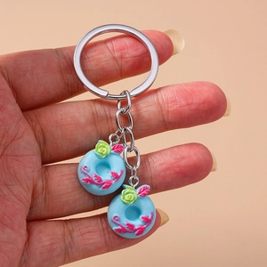 Handheld view of a creative silver keychain featuring two blue donut charms with pink flowers