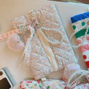 Détail de pochette matelassée fleurie avec poignée en perles et pendentif cœur dentelle