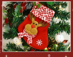 Close-up of a red Christmas stocking with reindeer applique hanging on a festive tree