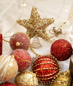 Detail of gold glitter star tree topper and red festive ornaments on snow background