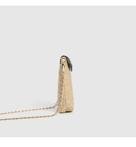 Detail of hand-woven straw mini bag with black vintage flap and golden chain strap