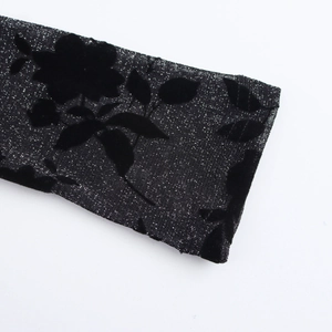 Elegant black knit dress sleeve featuring textured velvet floral patterns and subtle shimmer