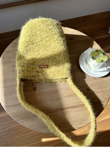 Detail einer weichen gelben Plüschtasche mit strukturiertem Stoff auf einem Holztisch