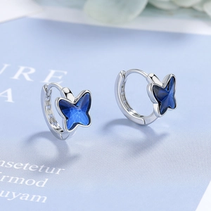 Macro shot of silver butterfly hoop earrings with deep blue transparent accents