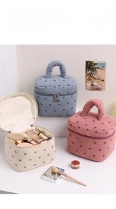 Detail of corduroy makeup bag with embroidered hearts and heart-shaped metal zipper puller
