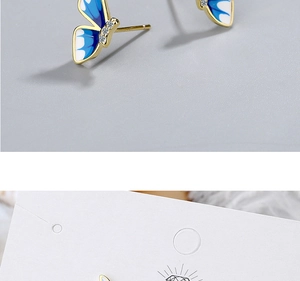Close-up of blue enamel butterfly stud earrings with gold edges and small crystals