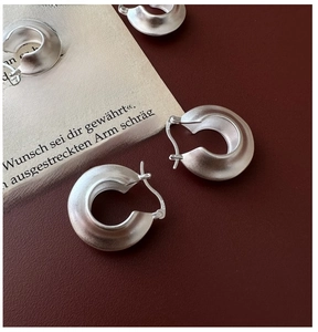 Detailed macro view of S925 sterling silver hoop earrings with a matte brushed finish