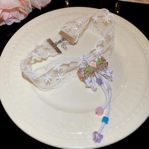 Detail of lace choker with floral embroidery, butterfly pendant and colorful beads