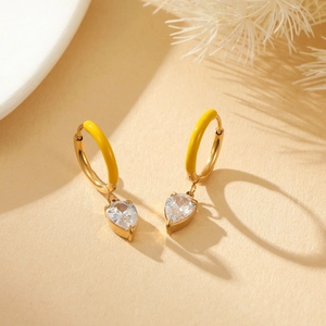 Detailed shot of golden hoop earrings with yellow enamel and heart-shaped crystal stone