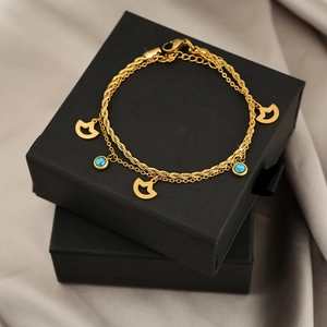 Detail of double-layer gold chain bracelet with blue lapis beads and fan charms