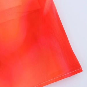Detailed close-up of vibrant orange scarf dress with precision white stitching finish