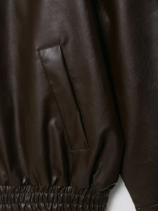 Detailed close-up of dark brown faux leather pilot jacket with side pocket and elastic hem