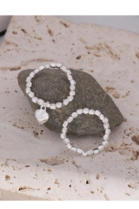 Detail of silver beaded rings with heart charm on natural stone aesthetic background
