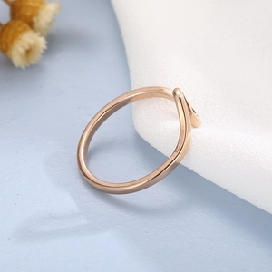 Close-up of minimalist rose gold wave ring on blue background with white silk