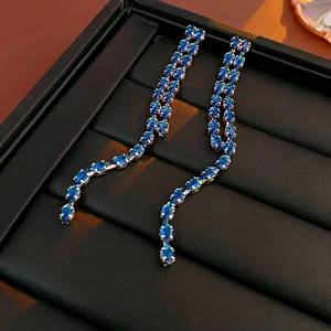 Close-up of blue teardrop gemstones and silver tassels on elegant long drop earrings