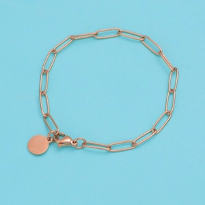 Close-up of rose gold paperclip link bracelet with round pendant and lobster clasp detail
