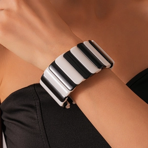 Close-up of a wide elastic bracelet featuring striped black and white acrylic segments
