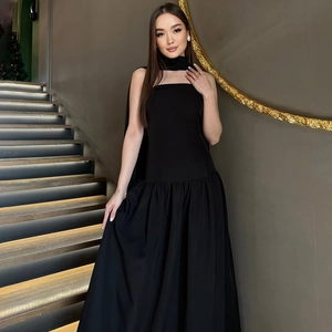 Elegant black maxi dress with halter scarf neckline on a model in a luxury interior