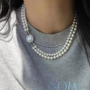 Double-layered gray pearl necklace featuring a square shell buckle on female model