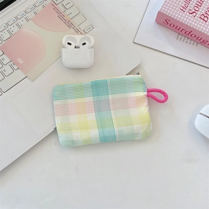 Macro detail of rainbow plaid fabric pouch with pink lanyard on a clean white desk