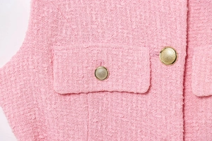 Close-up of pink tweed fabric texture with gold decorative embossed metal buttons
