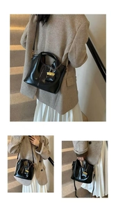 Detailed view of a black glossy oil wax leather tote bag with metal lock charm on a model