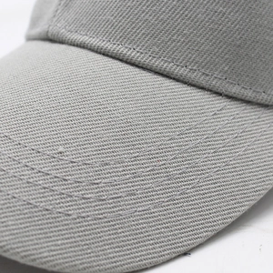 Macro detail of a gray baseball cap showing twill fabric texture and parallel brim stitching