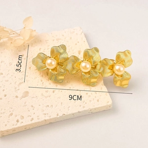 Detailed view of a 9cm golden flower hair clip with pearls on a natural stone base