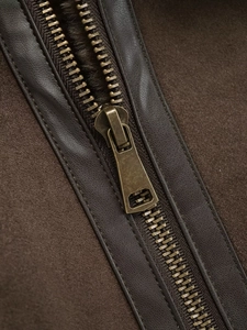 Detailed macro view of a bronze metal zipper on a brown faux suede jacket with leather trim