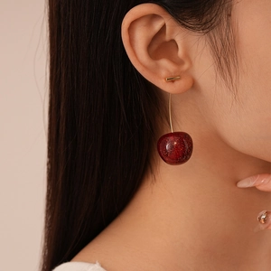 Close-up of red resin cherry earrings with glitter and gold curved metal stems