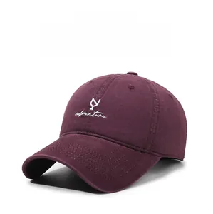 Detailed close-up of white adventure embroidery on a burgundy cotton baseball cap