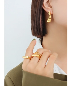 Gros plan sur des boucles d'oreilles lave plaquées or 18K et des bagues géométriques