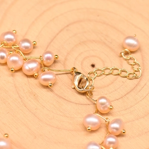 Elegant multi-layered pink pearl bracelet set with golden lobster clasp on wood background