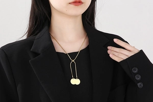 Detail of gold snake chain necklace with dual round pendants on a black blazer model