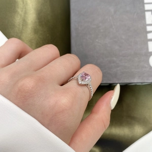 Macro shot of a heart-shaped pink zircon ring worn on a finger with a silver diamond band