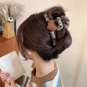 Détail d'une grande pince à cheveux imprimé léopard avec un cœur en peluche marron