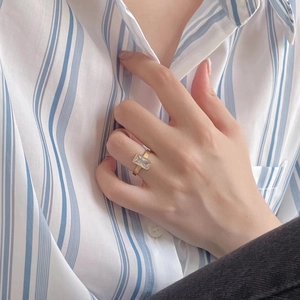 Detail of 925 silver gold ring with rectangular zircon stone worn on a finger