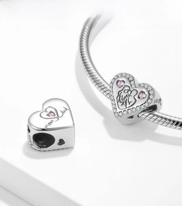 Macro detail of S925 sterling silver heart charm with mom & dad engraving and pink stones
