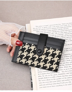 Close-up of houndstooth tweed card holder with snap closure held by elegant hands